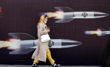 Una mujer iraní pasa junto a una enorme pancarta antiisraelí con imágenes de misiles, en Teherán, Irán.