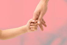 Imagen de un bebé dando la mano a su madre.