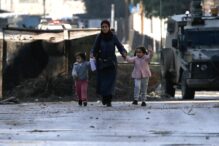 Una madre palestina con sus hijos salen del campamento de Jenín.