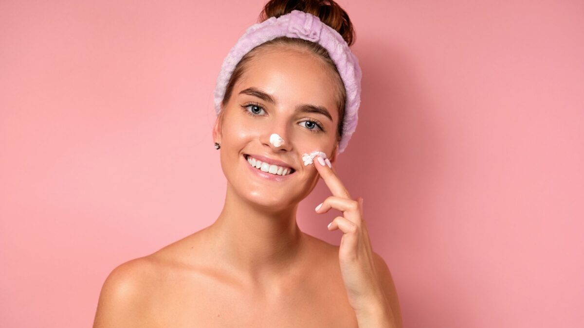 Una chica se aplica crema solar.