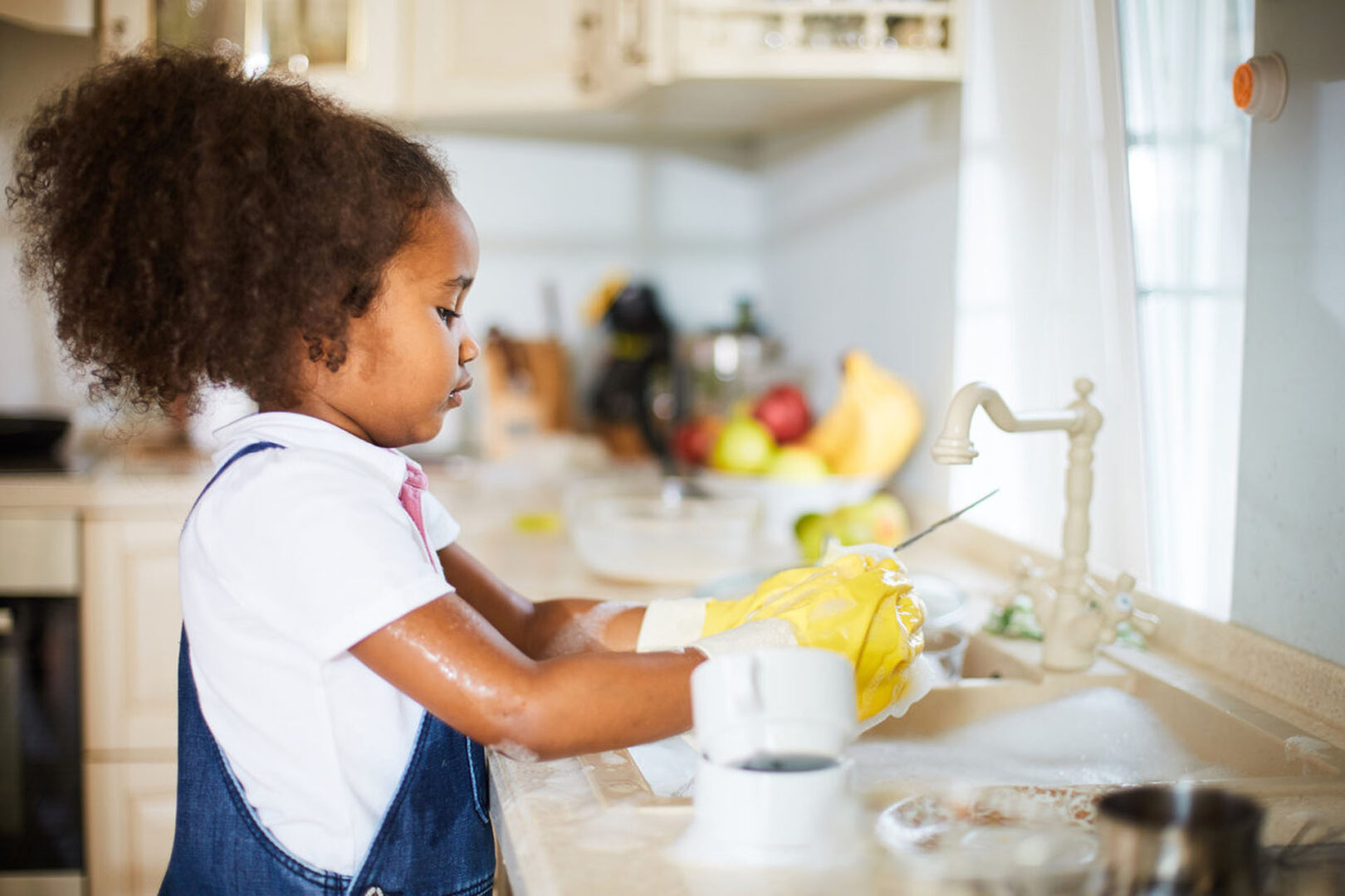 Una niña pequeña ayuda a lavar los platos
